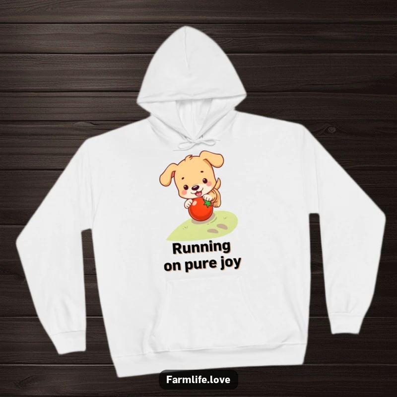 Funny hoodie depicting a playful puppy chasing a rolling tomato down a slope, bringing cozy humor and pet love.